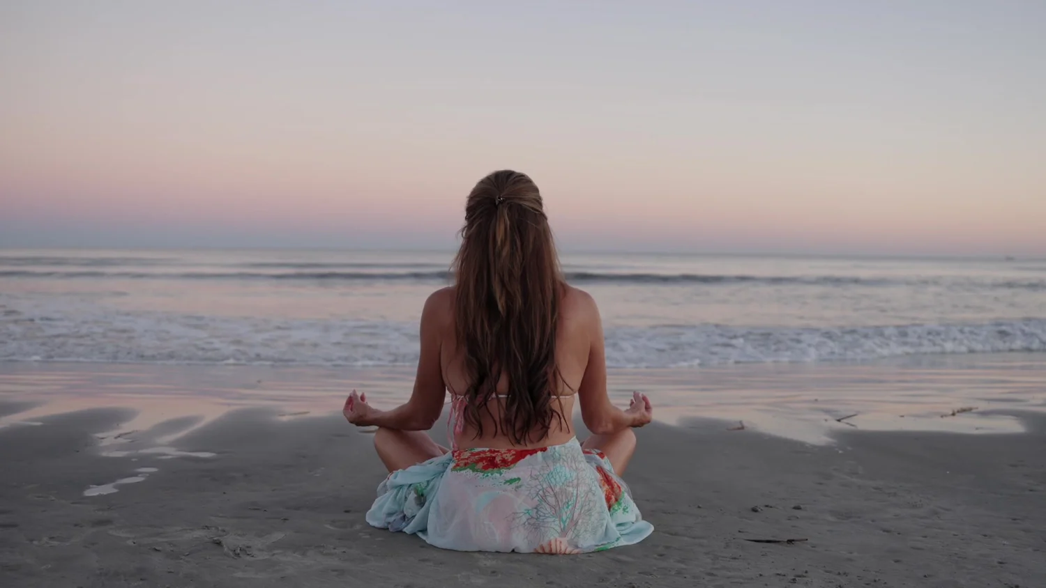Beach meditation beneath a pastel sunset sky, from the Longevity brand film