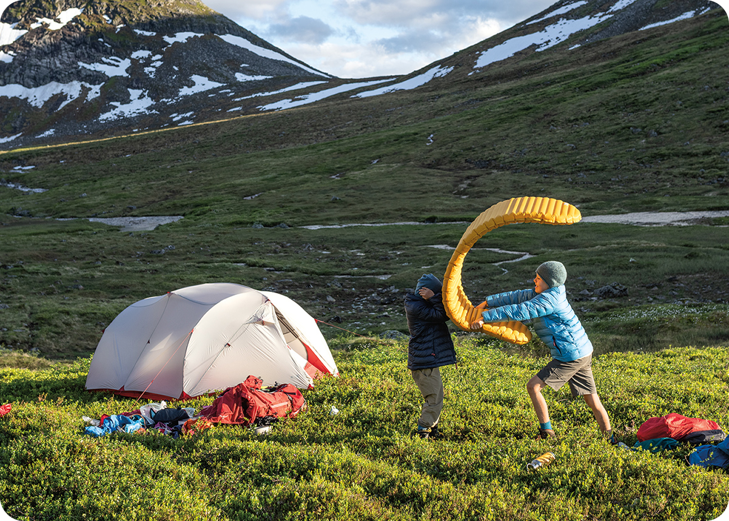 Two children play near a Big Agnes camping tent in a mountain meadow near Yellowstone National Park and Bozeman, Montana.