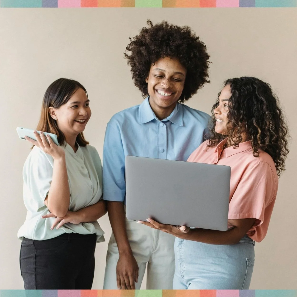 Three millennial women smiling and looking at a laptop during a consulting call.