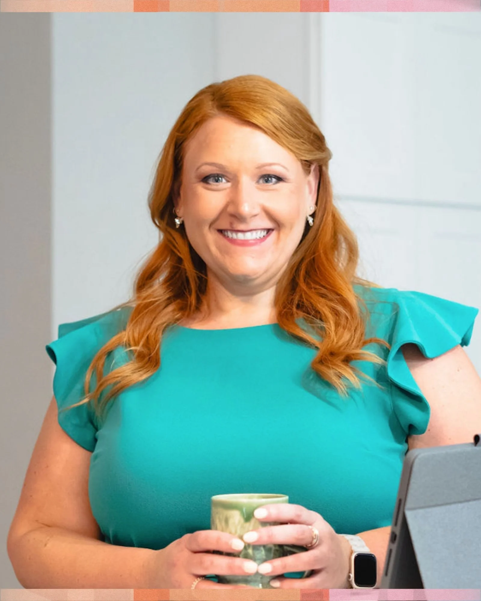 Cassandra Sissom, wearing a teal top, smiling, holding a green mug, standing in an indoor setting.