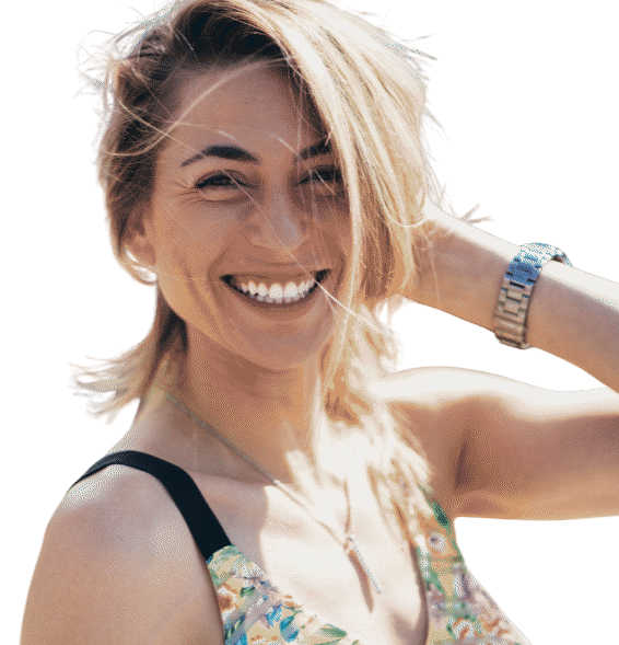A woman with blonde hair, smiling, wearing a colorful dress and a watch, outdoors.