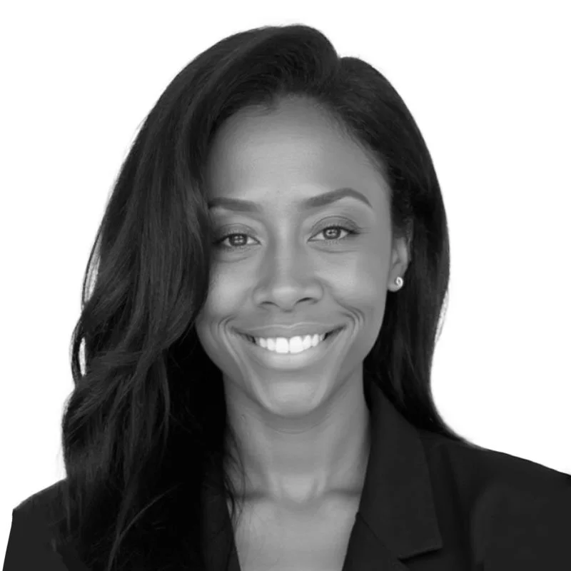 Black-and-white professional headshot of a smiling woman with long hair wearing a blazer