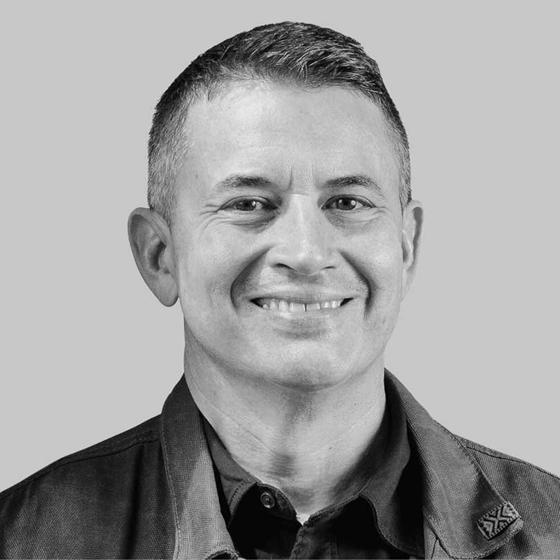 Black-and-white headshot of a smiling man wearing a collared shirt and jacket