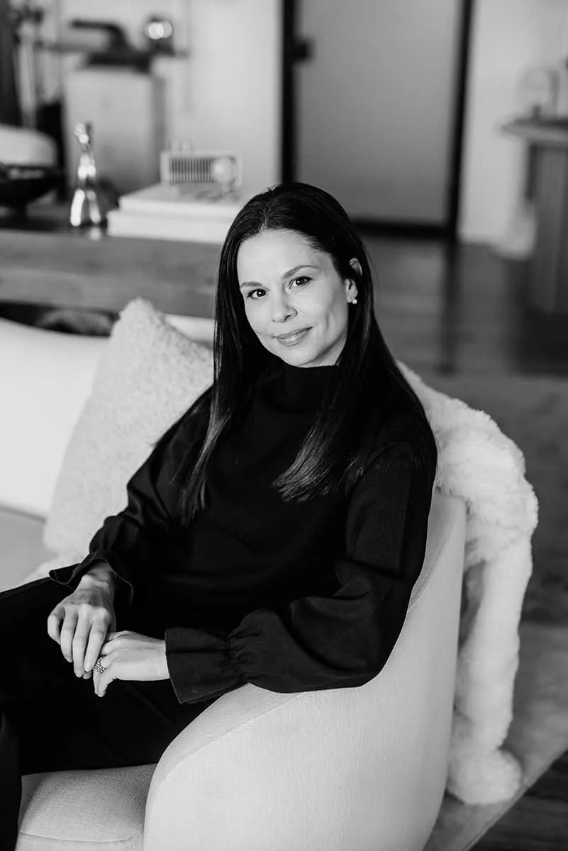 Black-and-white portrait of a woman in a black turtleneck sitting in an armchair at home