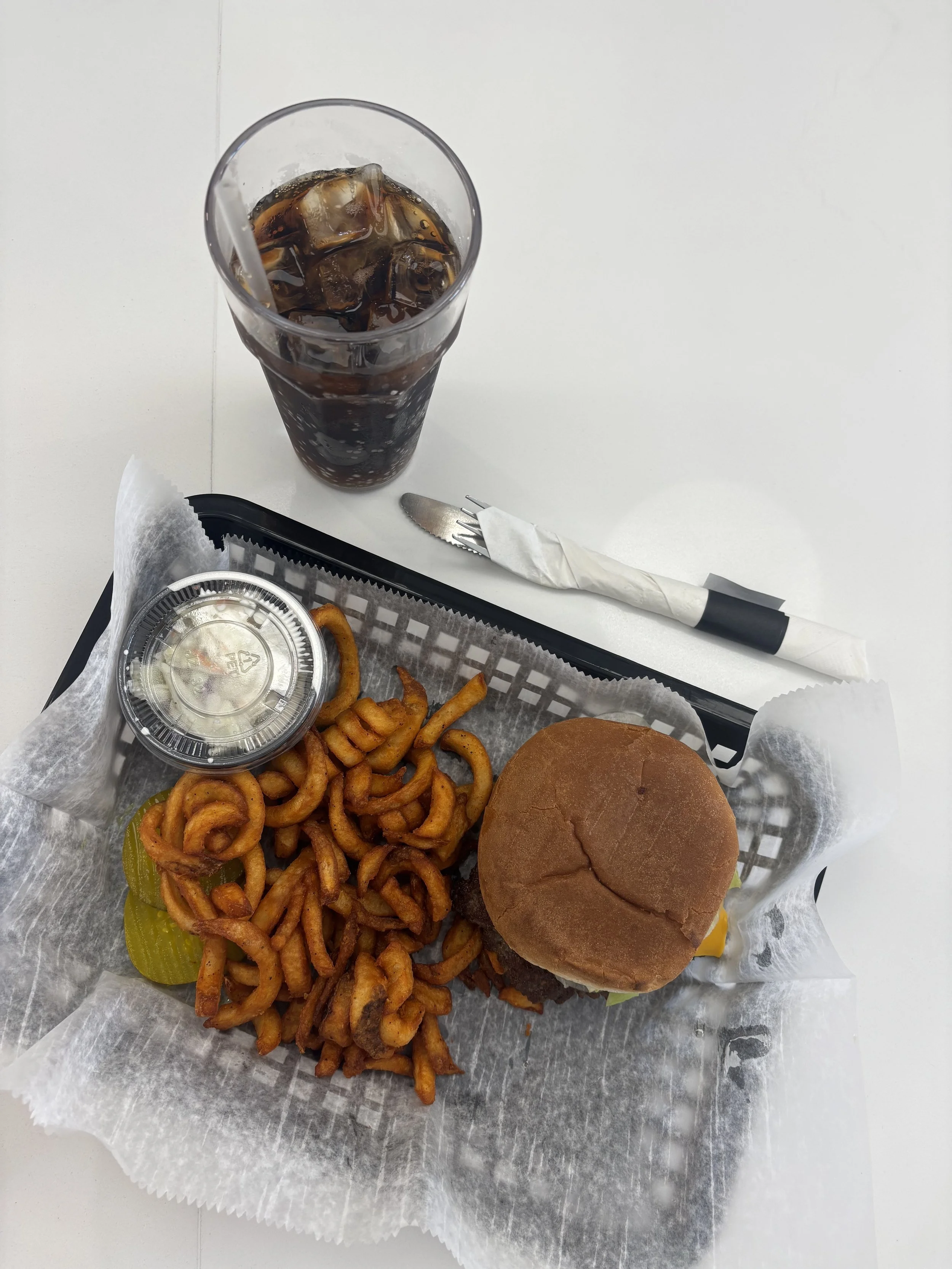Smash burger served with curly fries and a Diet Coke at Sally’s Diner