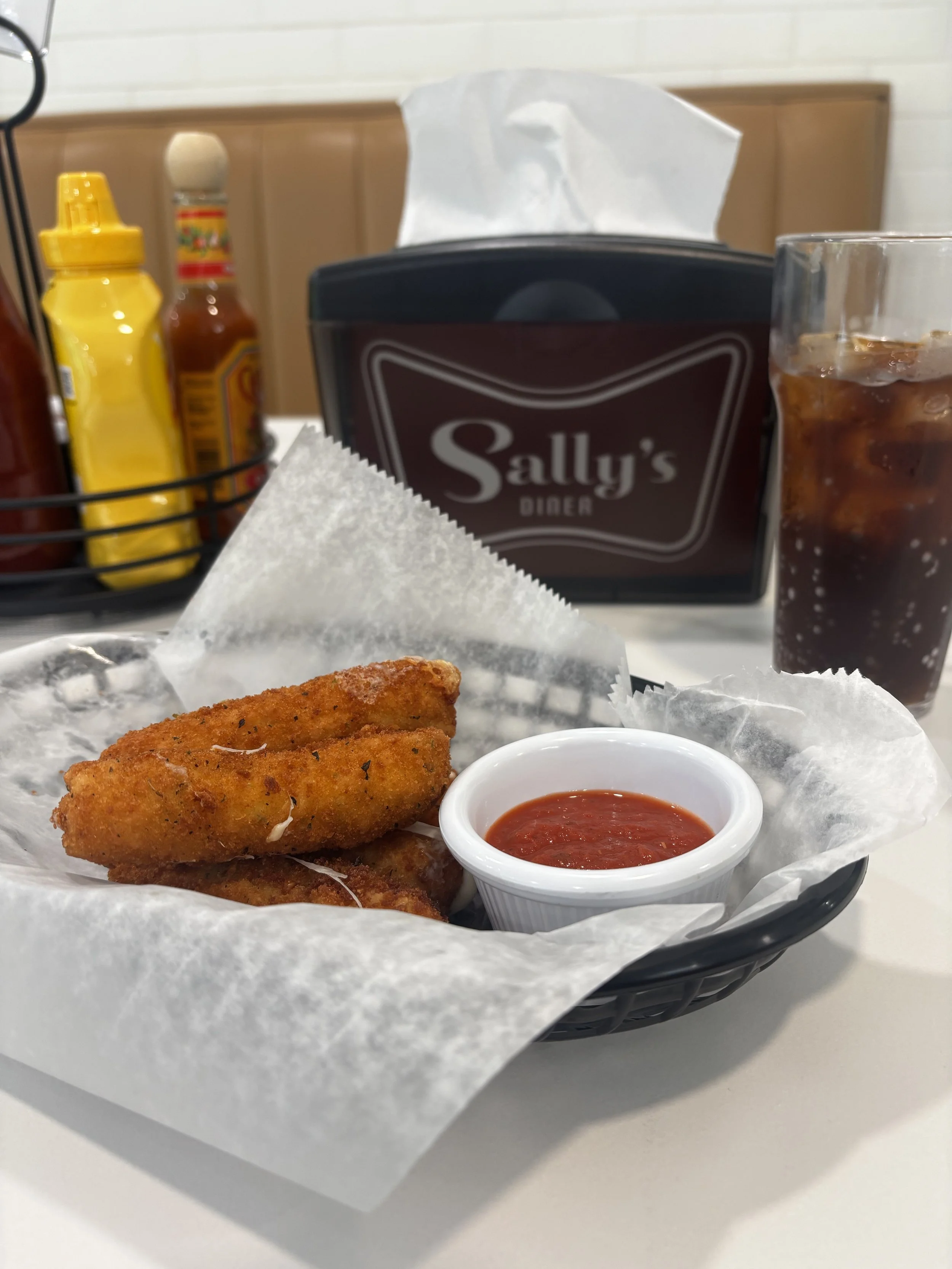 Crispy mozzarella sticks served with marinara dipping sauce at Sally’s Diner