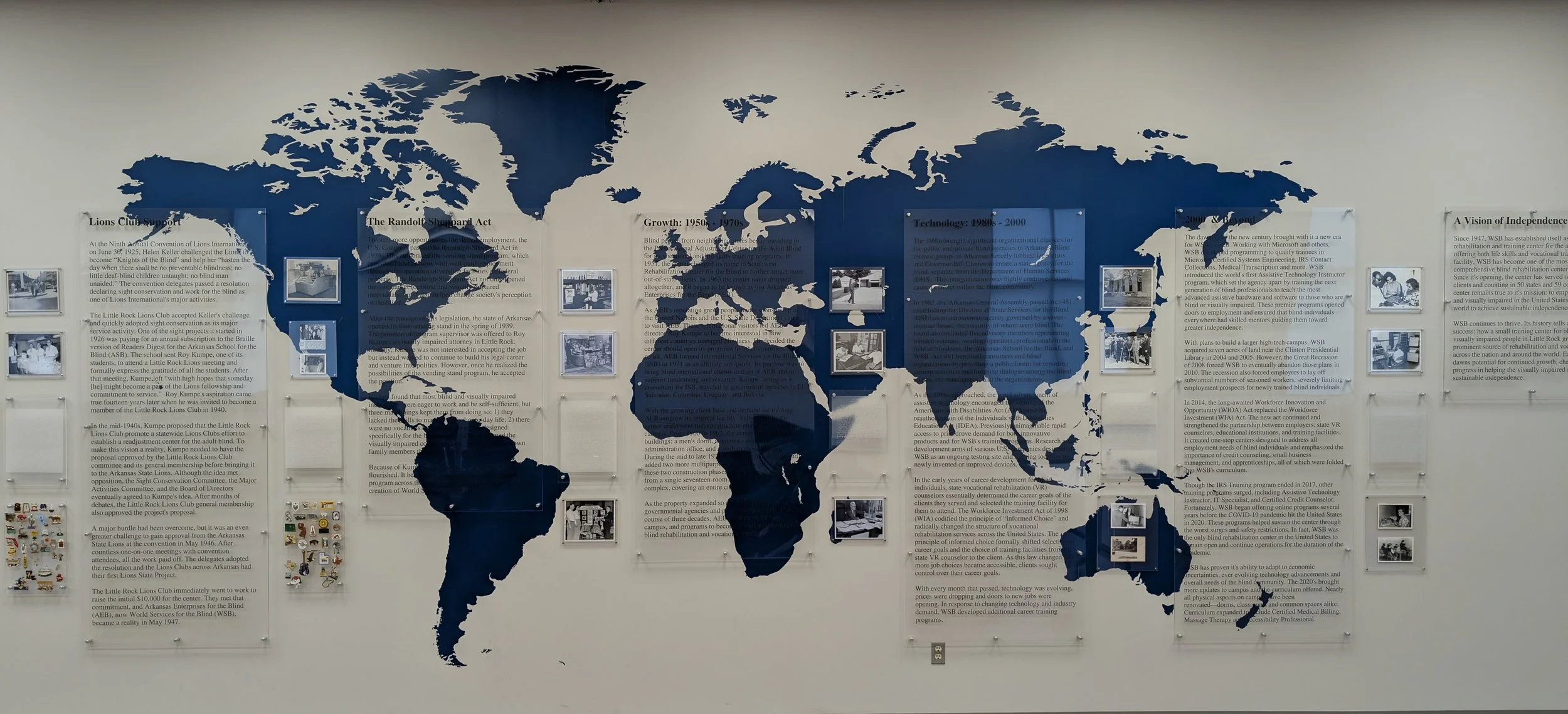 World map mural with surrounding informational posters and photographs on the wall.