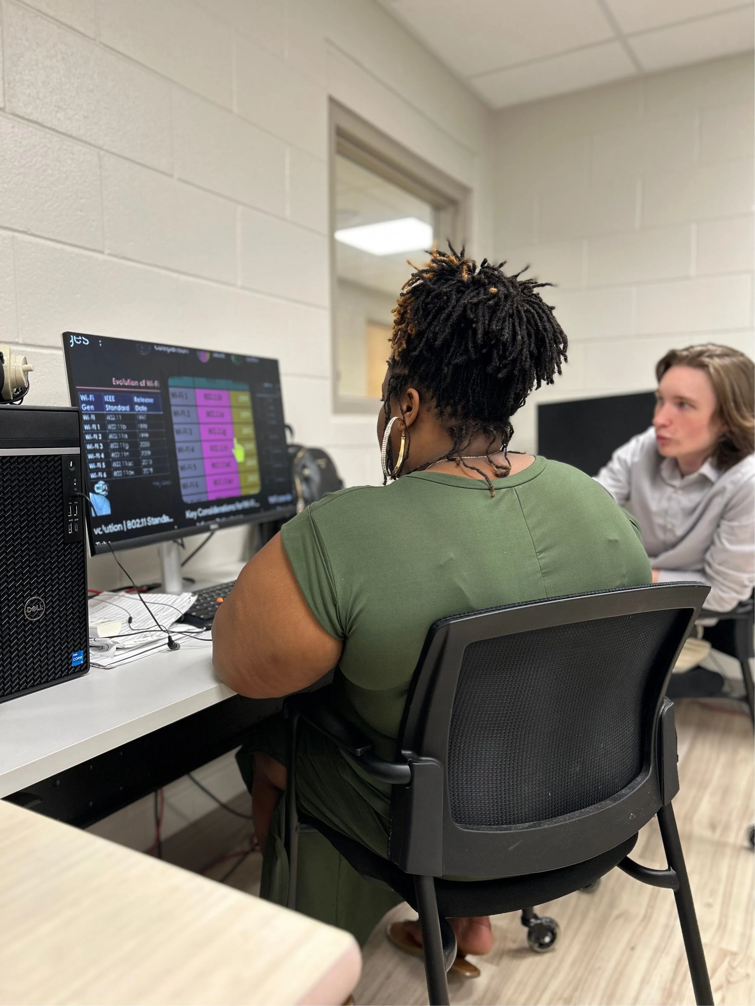 Image of a teacher explaining a lesson to a student in the computer lab