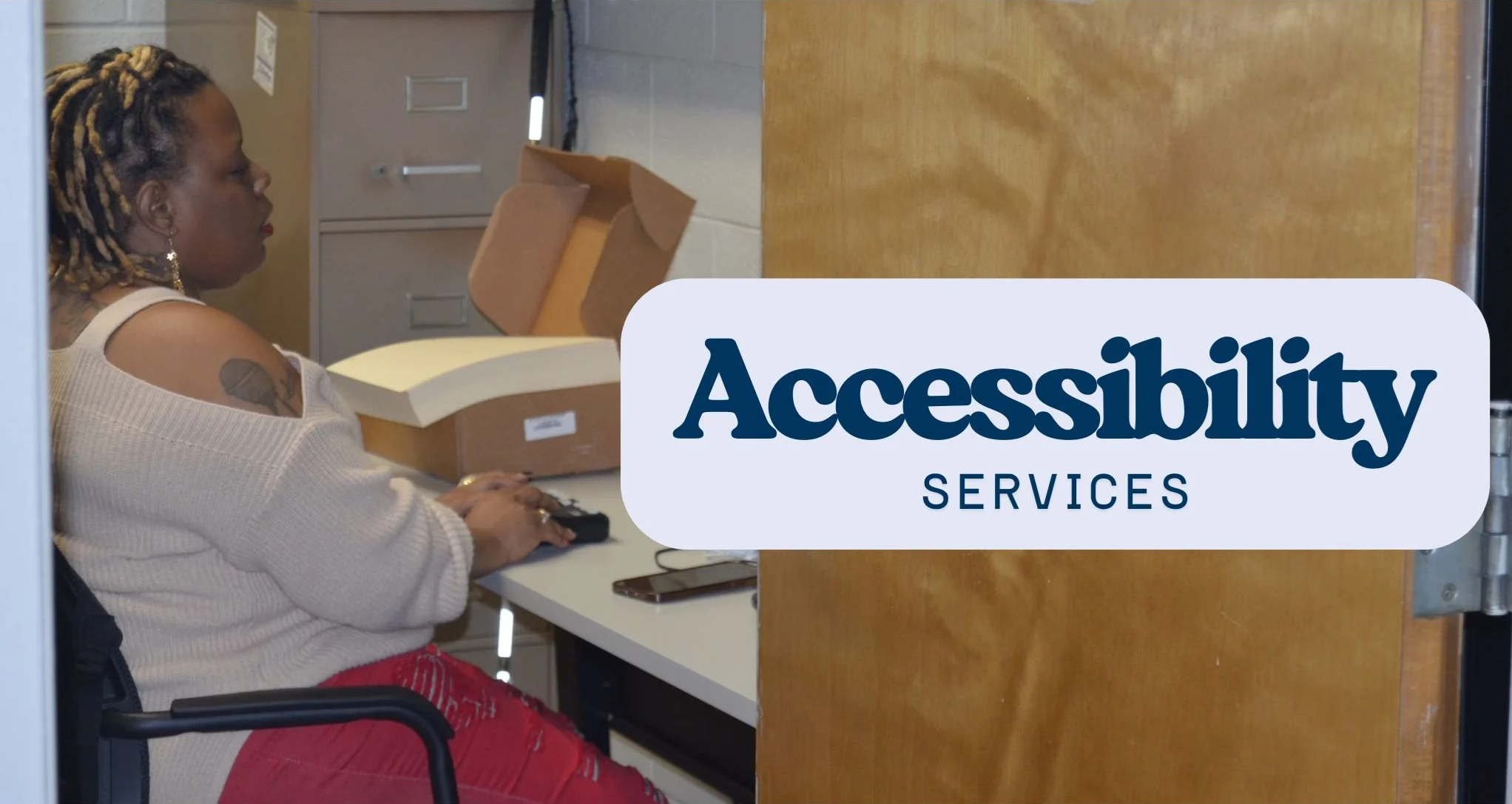A woman sits at her desk using a braille reader. Her white cane is leaned against a file cabinet in the corner. The words "Accessibility Services" are across the image.