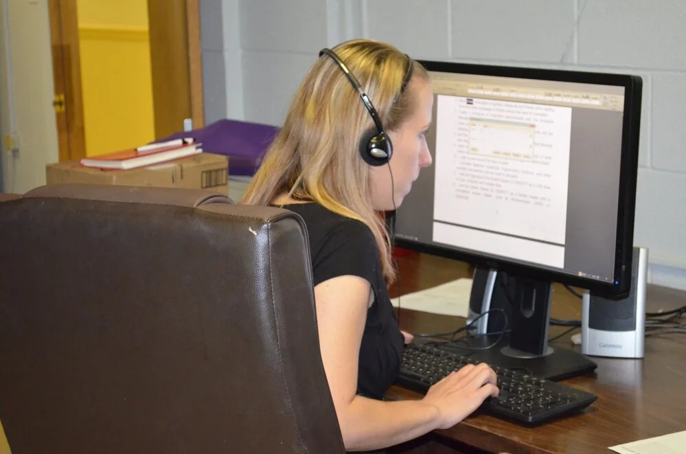 Client leaning into a computer using a low vision aid