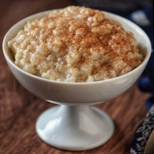 Creamy rice pudding topped with cinnamon in a white dessert bowl