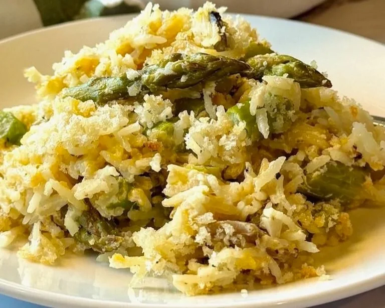 A plate of cooked rice mixed with asparagus and topped with grated cheese.