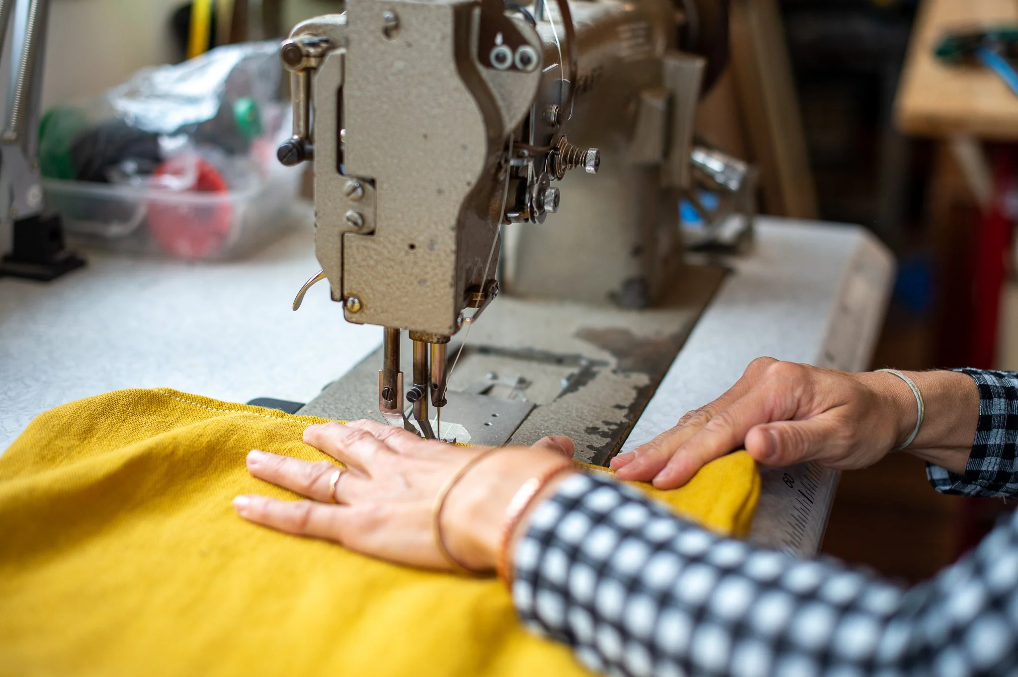 Une personne utilise une machine à coudre pour fabriquer un vêtement en tissu jaune.