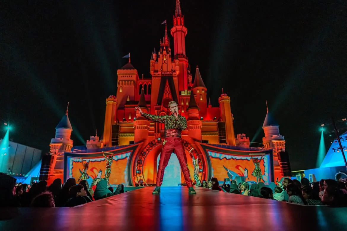 Fraser McAdam performing on a brightly lit stage in front of a castle