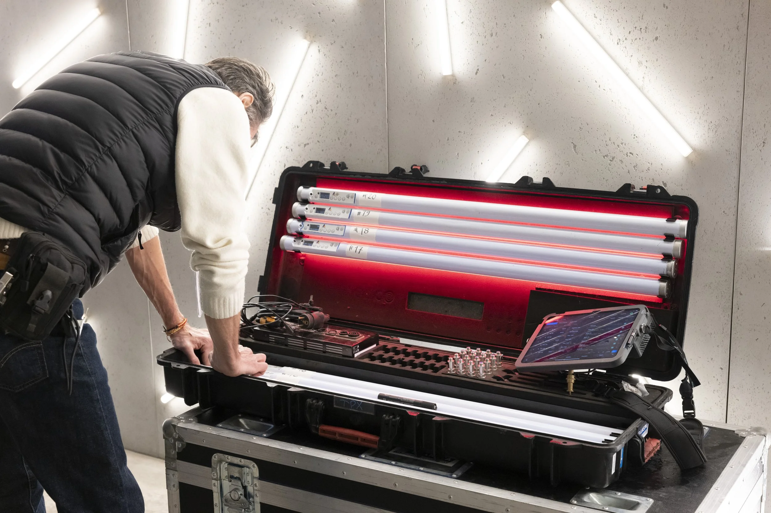 Technicien préparant des tubes lumineux LED rouges dans une mallette d’équipement, avec une tablette de contrôle.
