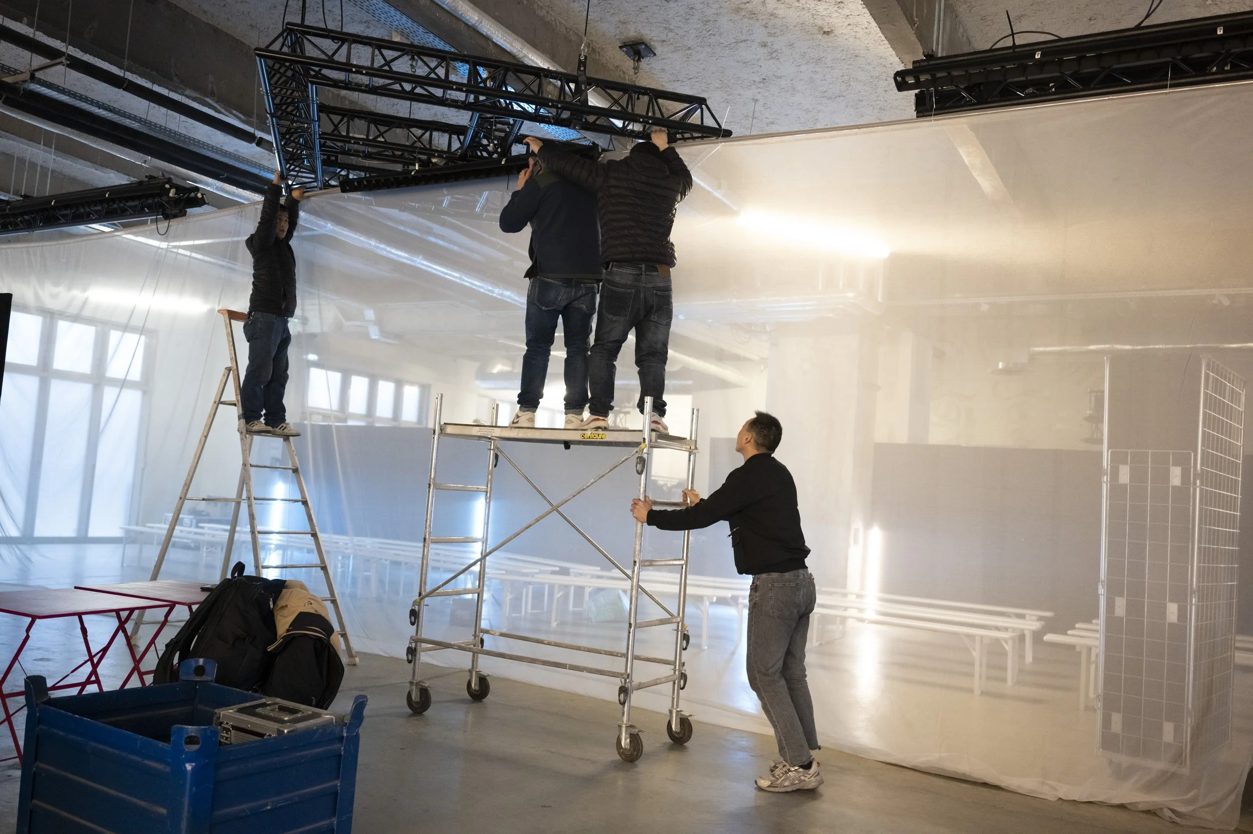 Équipe technique installant une structure d’éclairage sur échafaudages dans une salle événementielle.