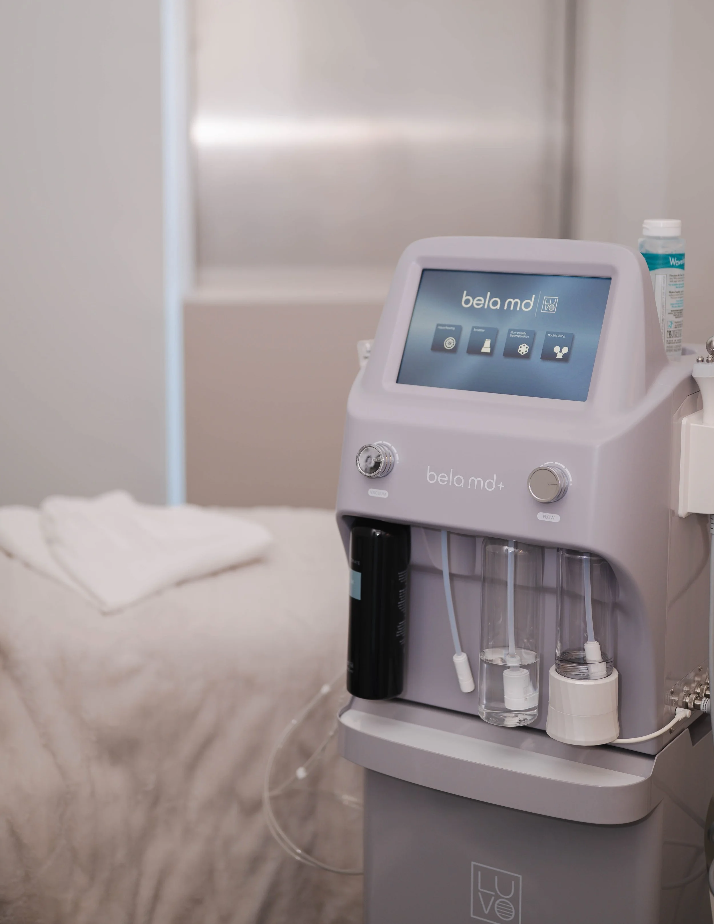 Une machine de traitement de peau appelée Bela MD, située dans un environnement médical ou clinique, avec des tubes et des accessoires attachés à la machine.