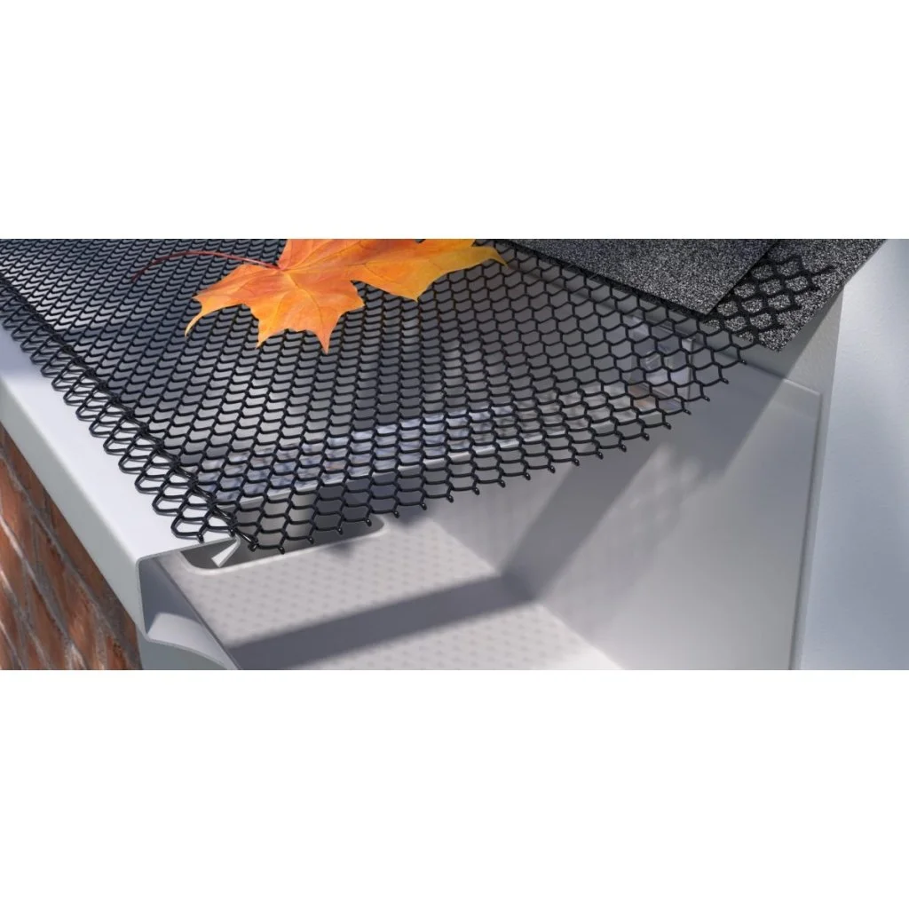 A black hexagonal mesh mat placed on a white surface with an orange autumn leaf on top and some black textured sheets nearby.