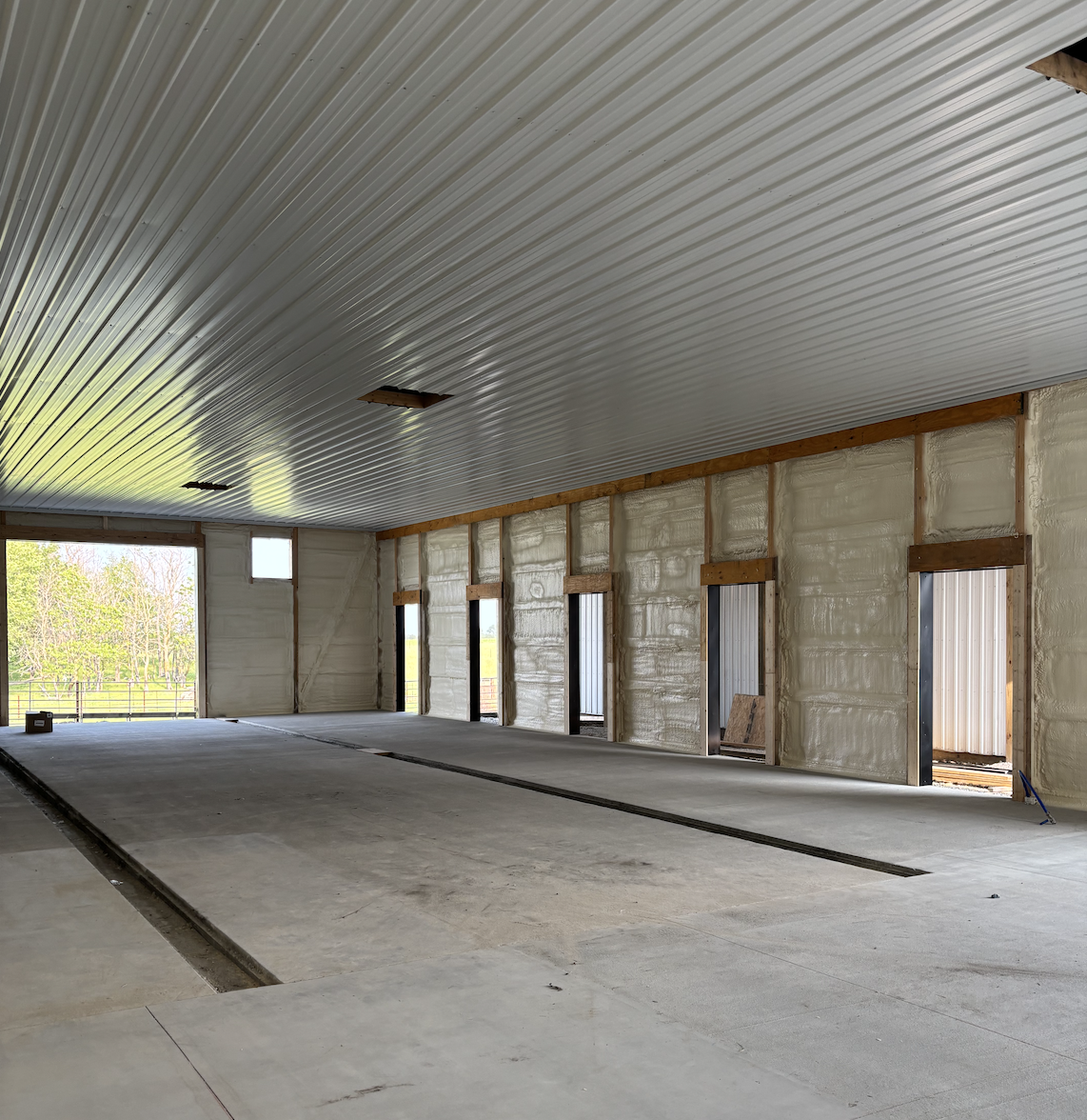 Interior of a building under construction with a metal ceiling, unfinished walls, and exposed door frames.