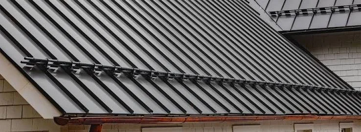 Close-up of a metal roof with parallel panels and a gutter system.