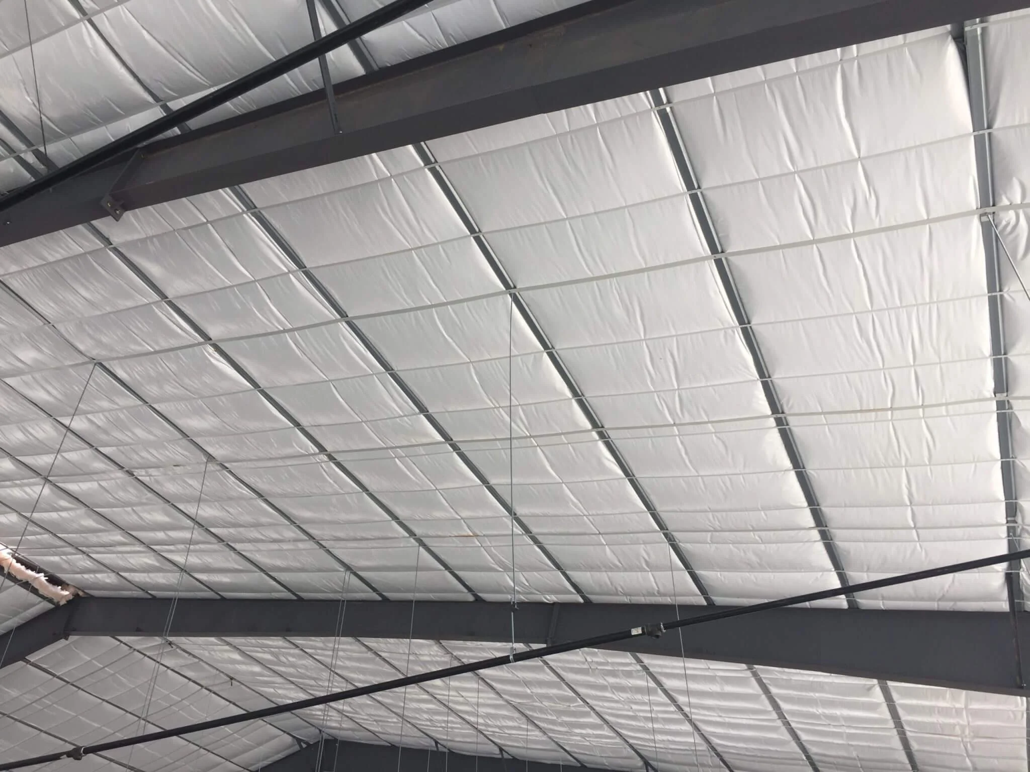 Looking up at the ceiling of a building with a metal framework and insulated panels.