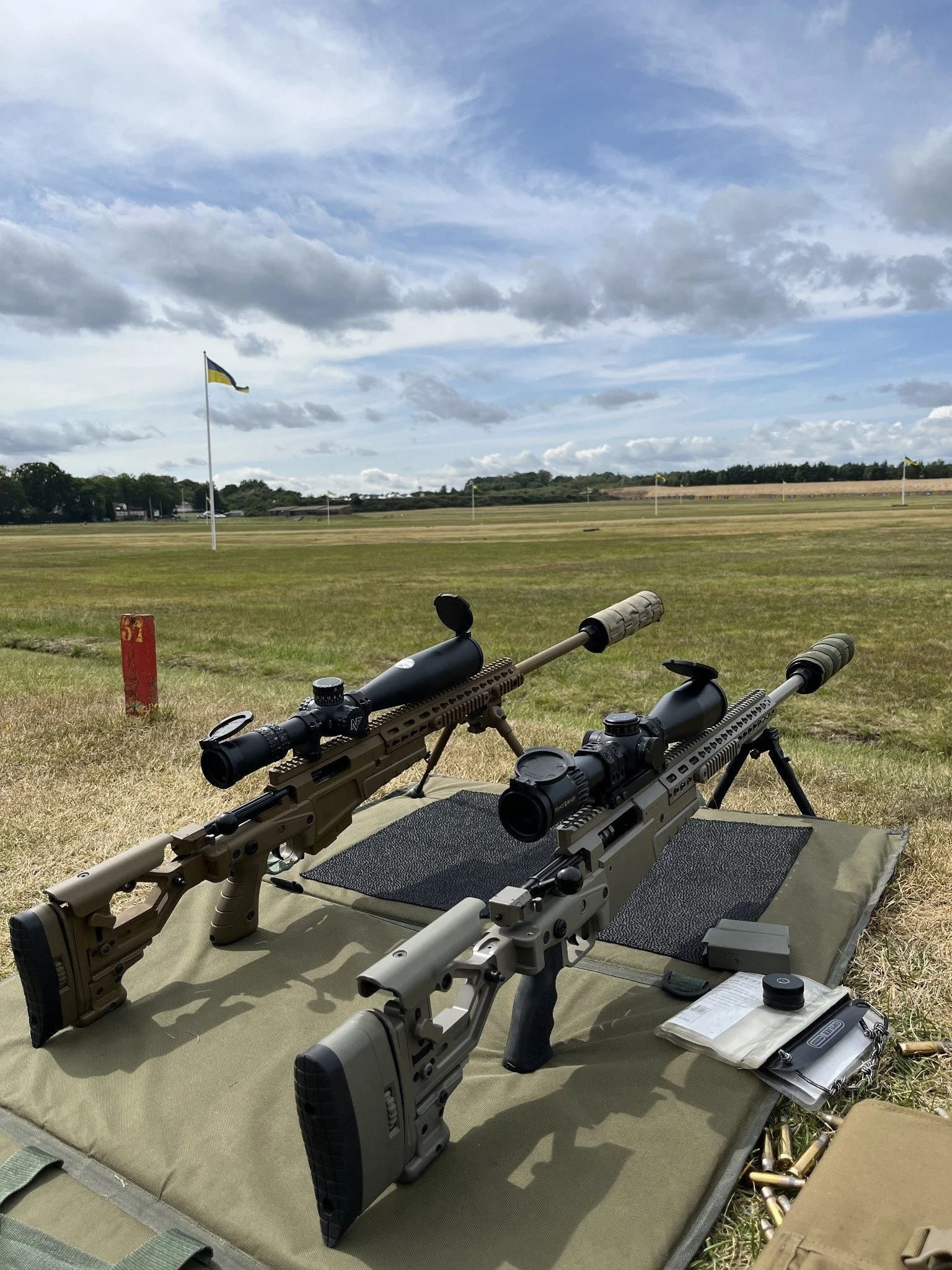 Two scoped rifles set up on an outdoor long-range shooting range