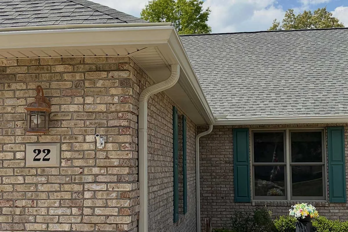 Close-up of a brick house exterior with a window featuring teal shutters, house number 22, and a hanging lantern light fixture.