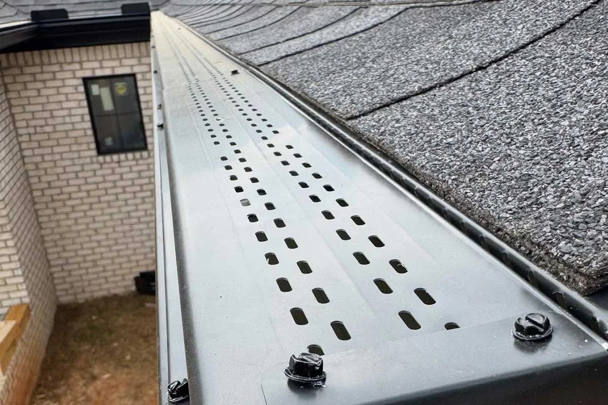 Close-up of LeafX gutter protection metal gutter guard installed on the gutter of a new brick house.