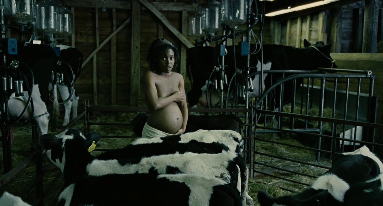 Kee reveals her pregnant belly to Theo inside a barn surrounded by cattle.