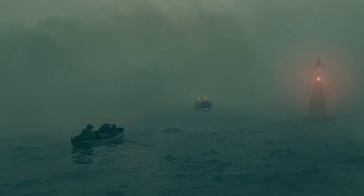 A large ship emerges through the fog beyond Theo and Kee’s small boat.