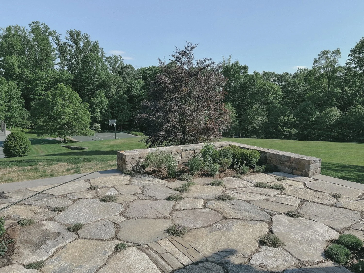 Natural stone terrace with a low retaining wall overlooking the grounds, Country Home, Redding CT