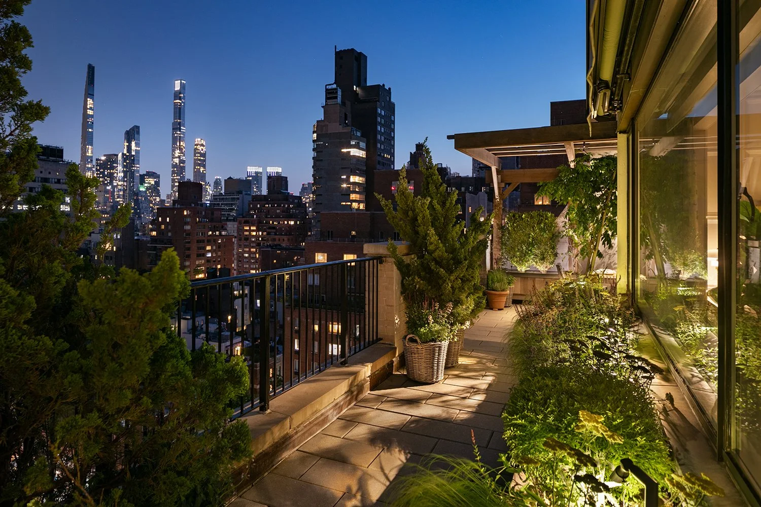 Lit terrace planting at night with the city skyline beyond, Upper East Side Penthouse