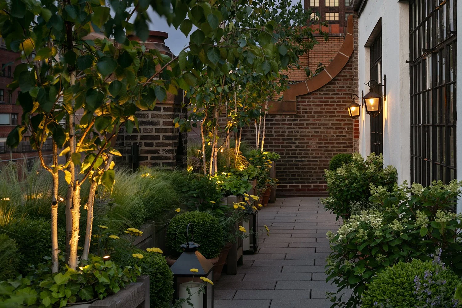 Uplit trees and layered planting along a quiet side terrace at dusk, Upper East Side Penthouse