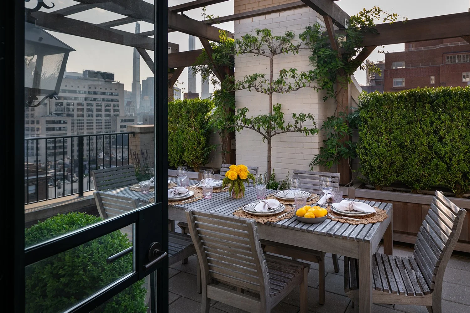 View through black-framed doors to the dining terrace and clipped hedges, Upper East Side Penthouse