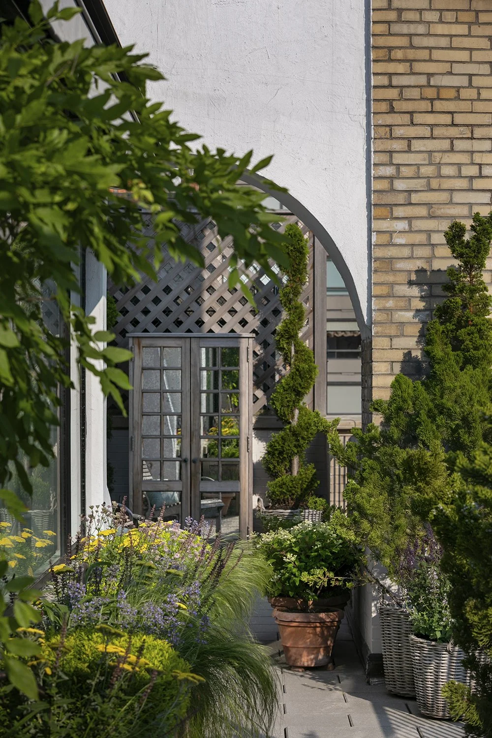 Climbing plants on an arched trellis between brick and white walls, Upper East Side Penthouse