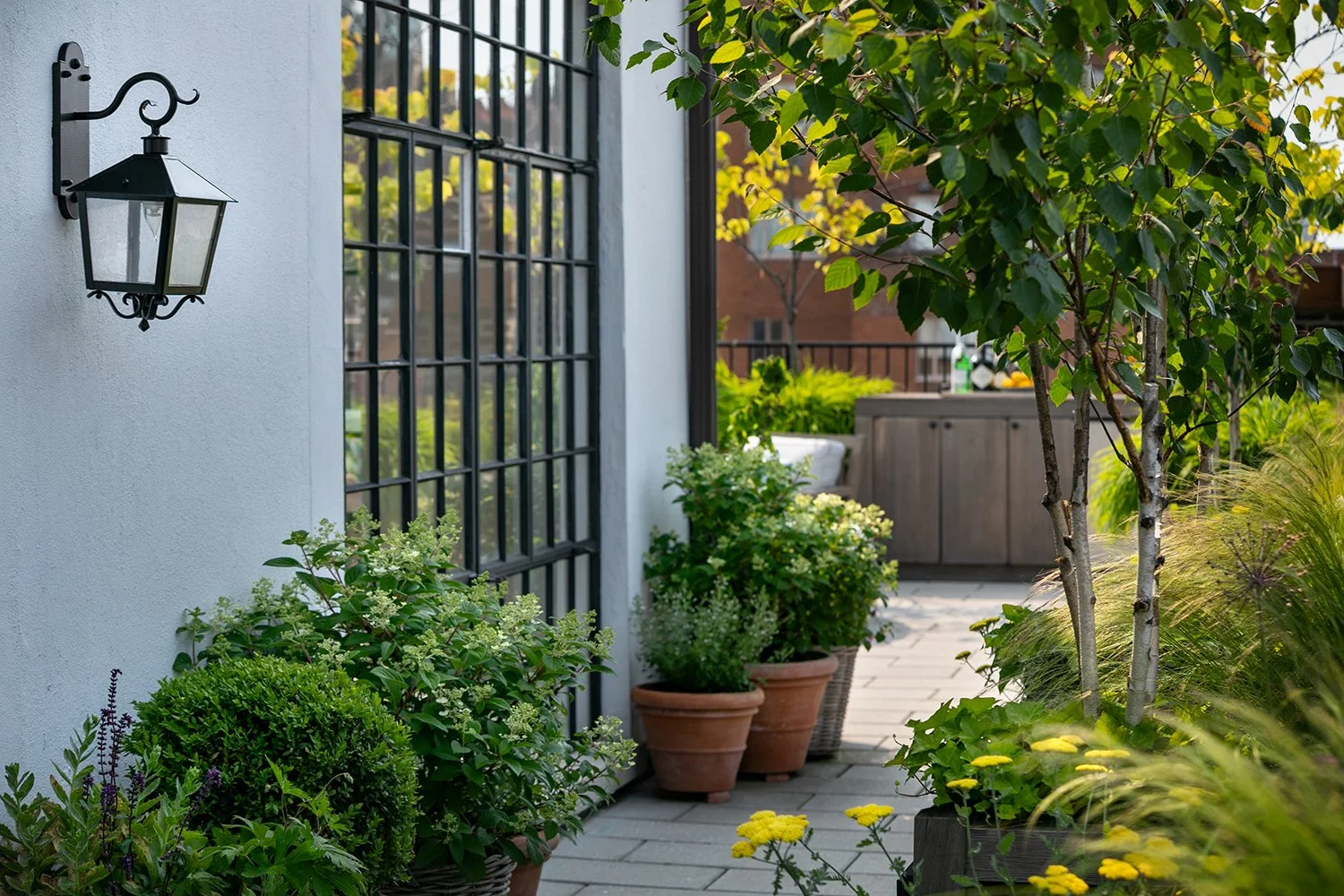 Wall lantern, black steel-framed doors and potted planting on the terrace, Upper East Side Penthouse