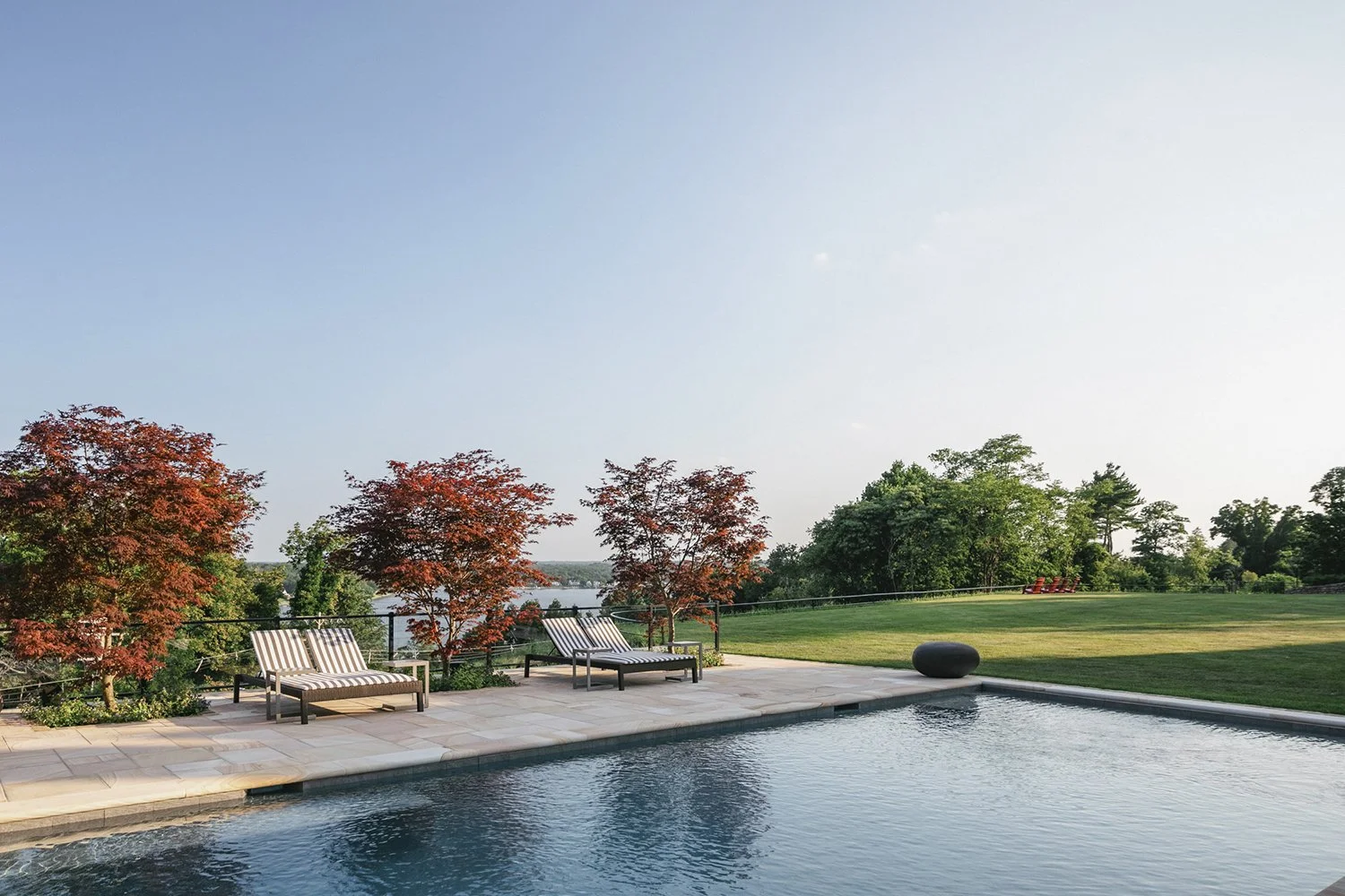 Pool and lounge chairs with red Japanese maples and the river beyond, Riverfront Estate, Navesink River