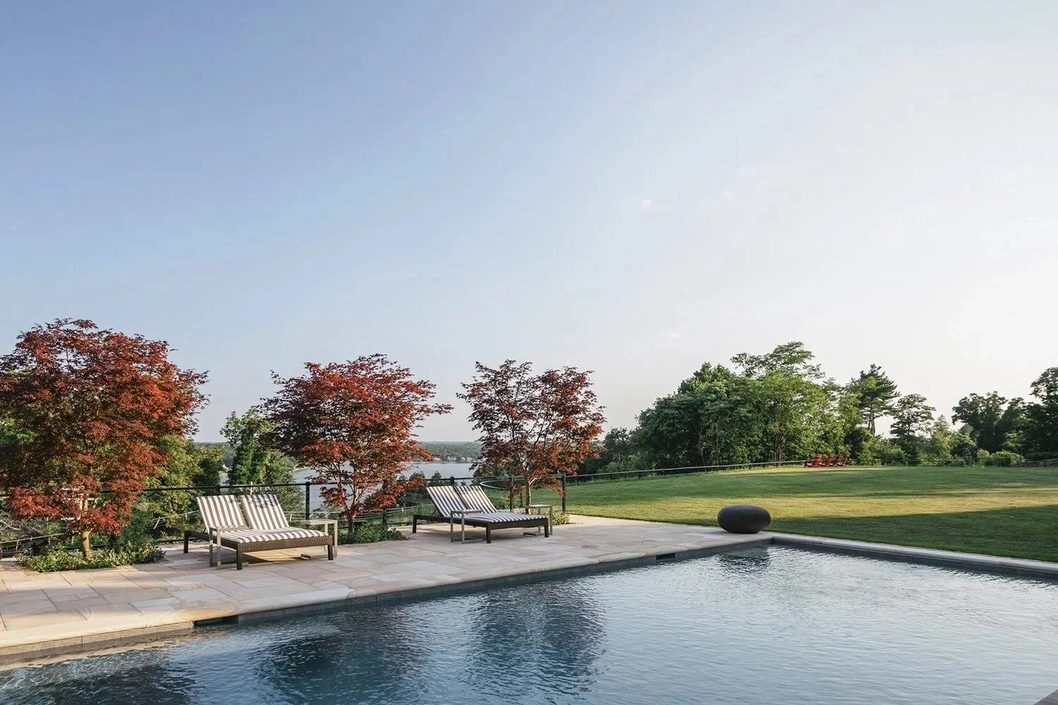 Pool and lounge chairs framed by red Japanese maples above the river, Riverfront Estate, Navesink River