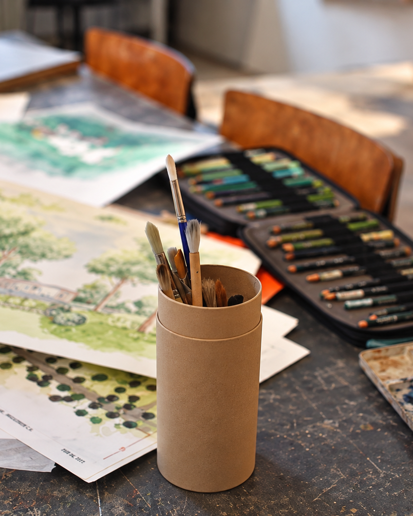 Watercolour paints and brushes beside garden sketches, David Eaton Associates