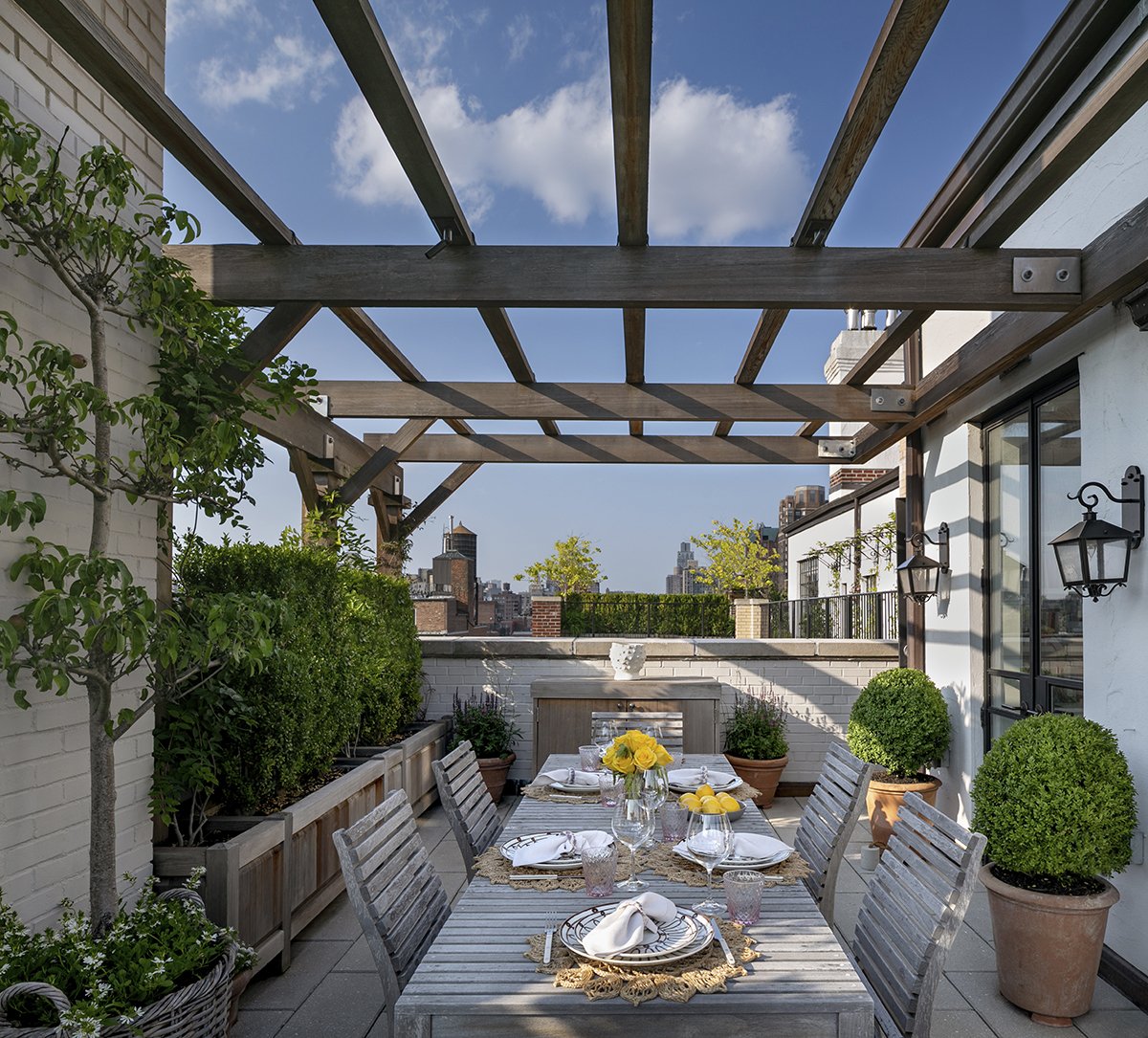 Dining table set beneath a timber pergola on the terrace, Upper East Side Penthouse