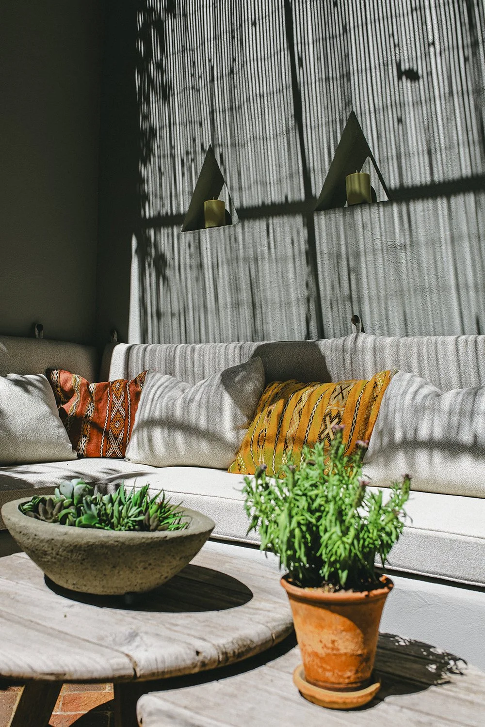 Potted herbs and a stone bowl on a timber table beside the cushioned bench, Townhouse Garden, Brooklyn