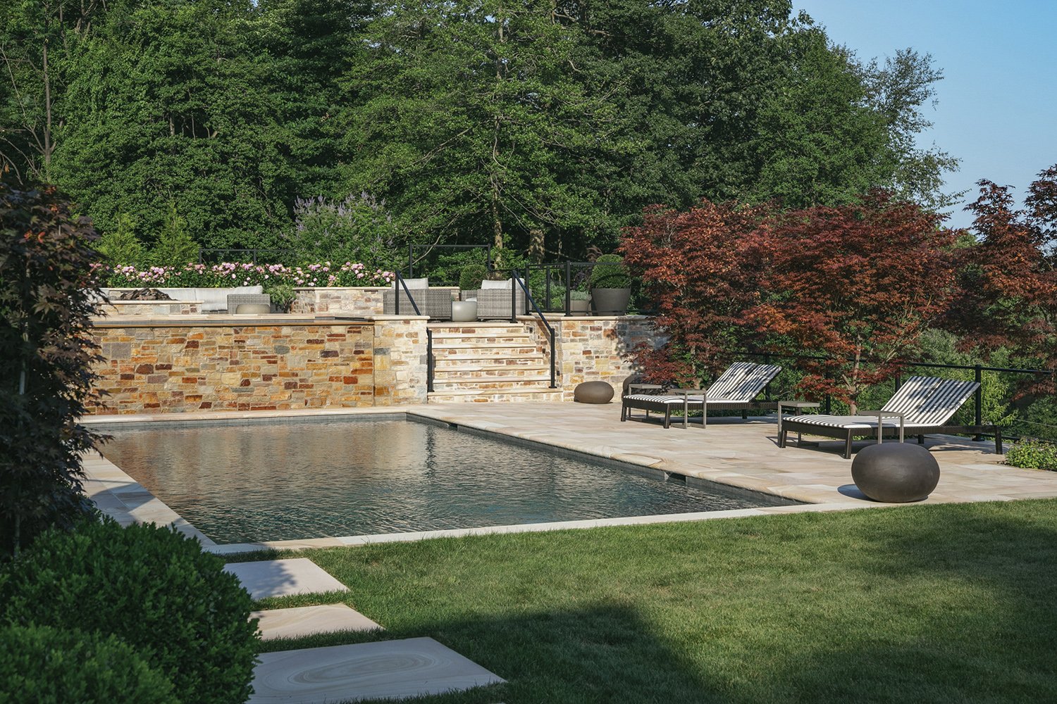 Pool and lounge chairs against a stone retaining wall with Japanese maples, Riverfront Estate, Navesink River
