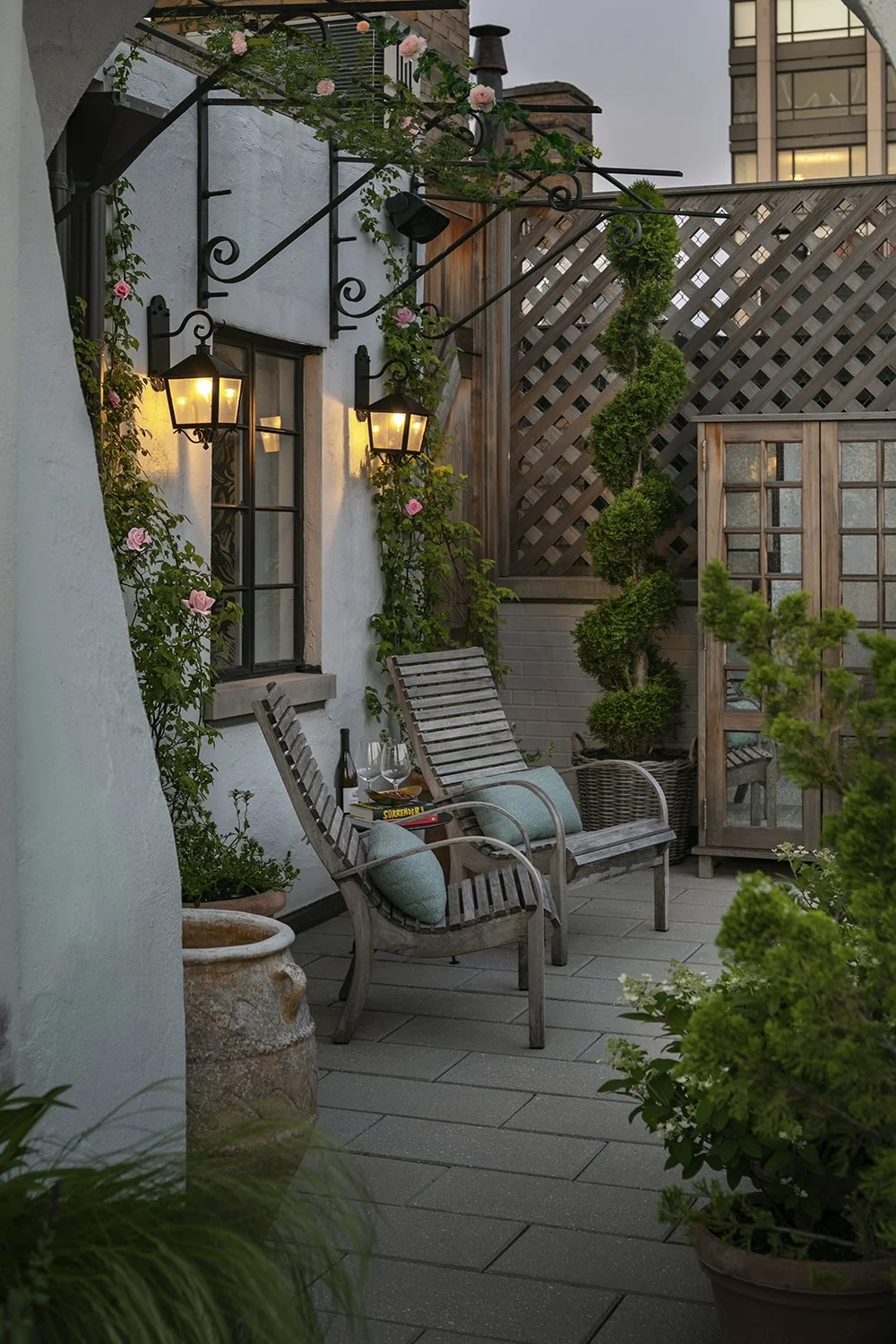 Sheltered seating nook with armchairs and wall lanterns beside the trellis, Upper East Side Penthouse