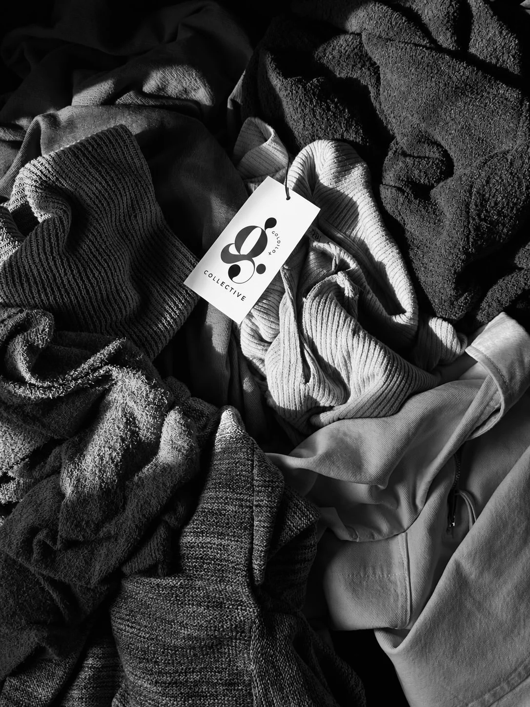 A pile of various textured clothes in black and white, with a visible tag that reads 'S. COLLECTIVE'.