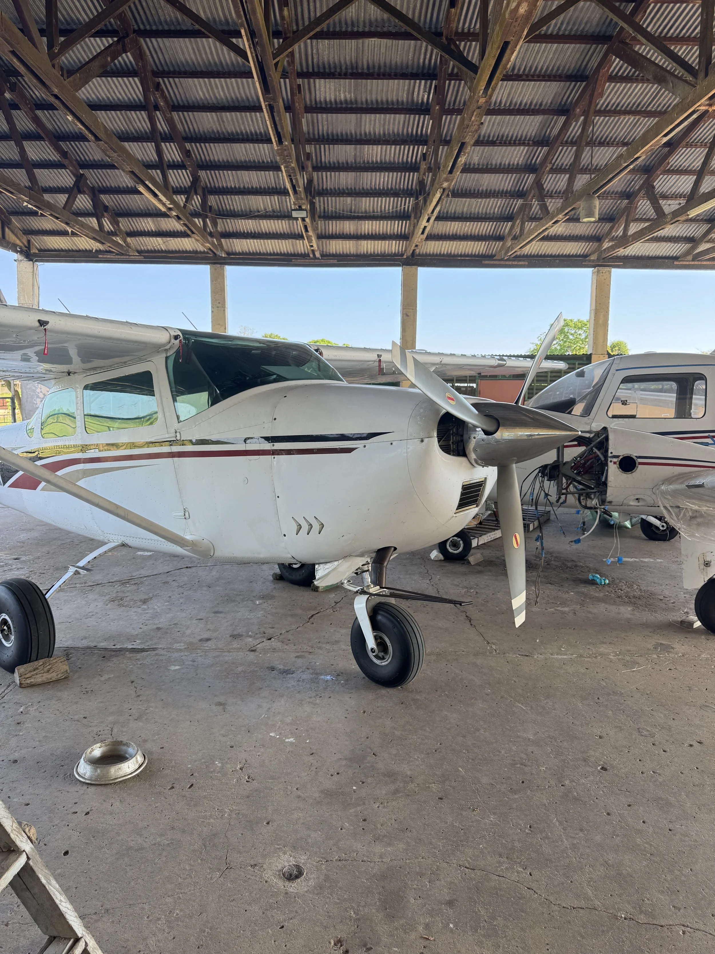 A small airplane inside a hangar, with some parts showing maintenance or repair work.
