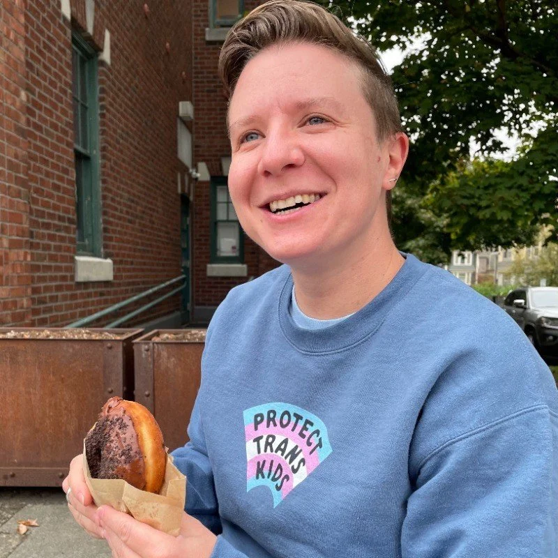 Genya eating a donut and supporting trans kids- two favorite activities.