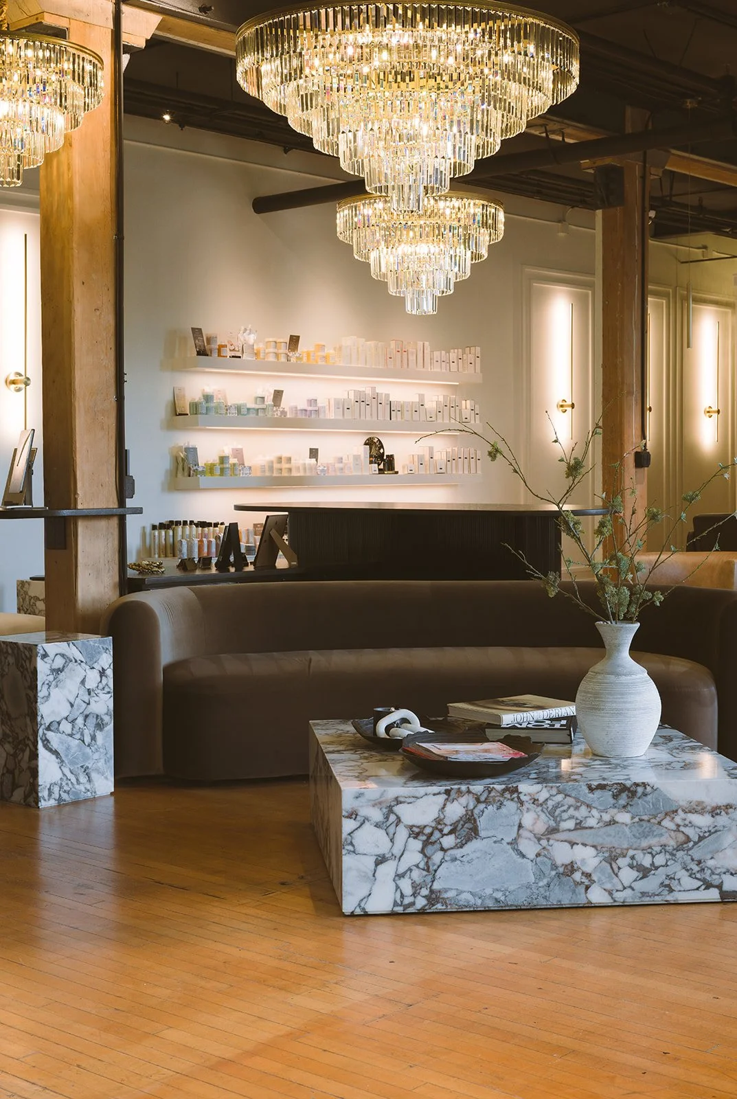 Luxurious interior of a boutique store with a modern chandelier, marble coffee table, and shelves with various products.