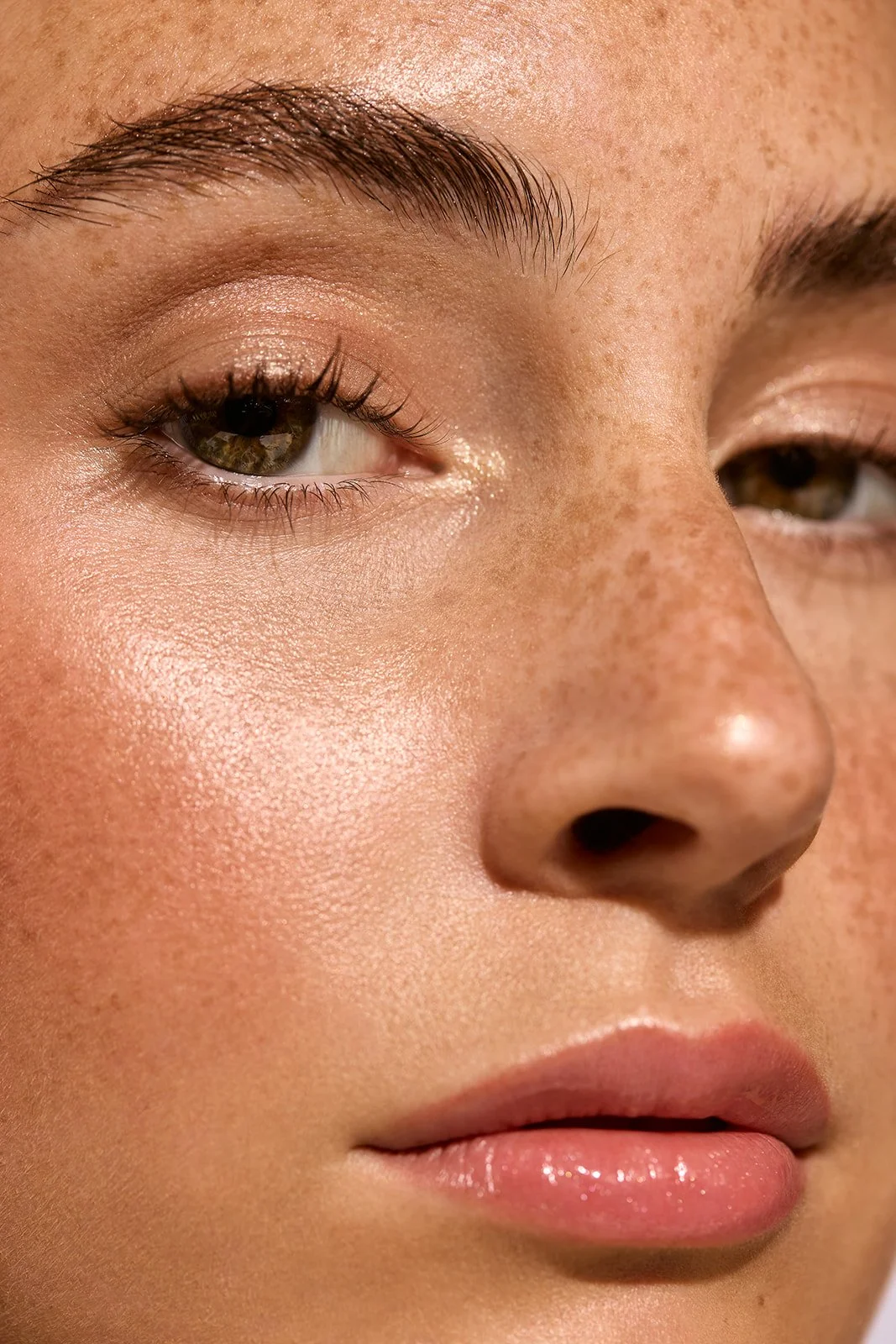 Close-up of a woman's face showing her eye, cheek, nose, and lips with natural skin tone and subtle makeup.