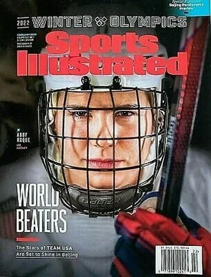 Close-up of a female hockey player wearing a helmet and face mask, holding a hockey stick, on the cover of Sports Illustrated Winter Olympians magazine.