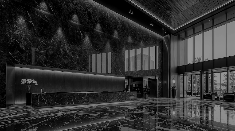 Modern hotel lobby with black marble floors, high black marble walls, and large glass windows and doors.